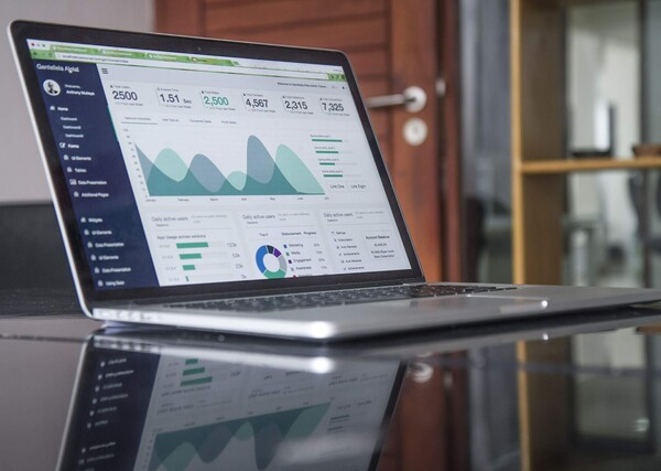 Laptop with stats sitting on a glass table in an office